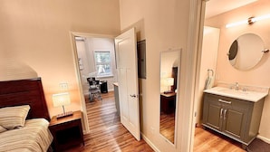 A bedroom with a bed, bedside table, lamp, and a mirror.