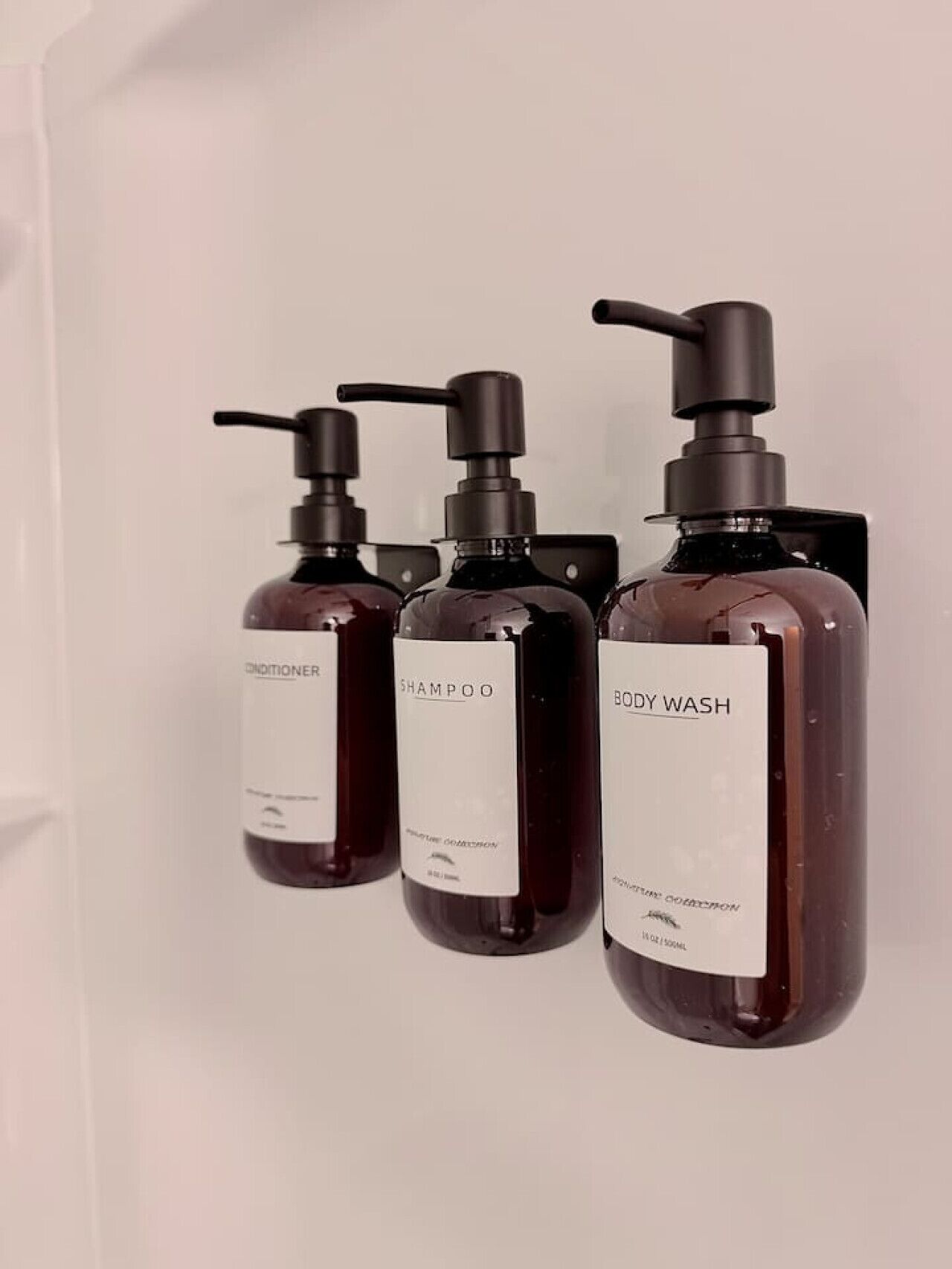 Three bottles of body wash, shampoo, and conditioner on a white surface.