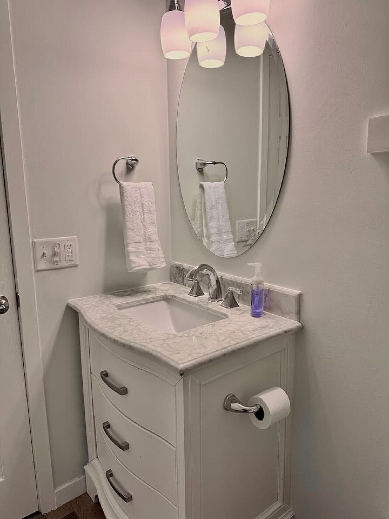 A bathroom with a white sink, a mirror, and a towel hanging on the wall.