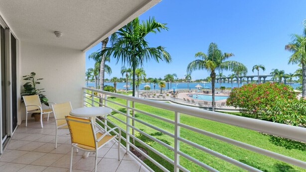 A balcony with a view of a pool and palm trees.