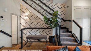 Un escalier moderne avec un mur orné d’un motif géométrique, un banc et une plante en pot.