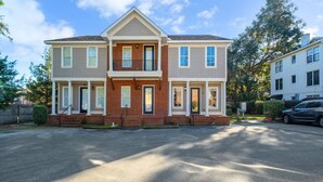 A two-story residential building with a central entrance, a covered porch, and a driveway. - Midtown Home, Pets Welcome! (Tallahassee)