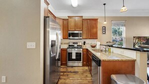 A modern kitchen with wooden cabinets, stainless steel appliances, and a granite countertop. - Midtown Home, Pets Welcome! (Tallahassee)