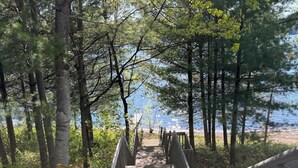 A wooden staircase leading to a beach, surrounded by trees.