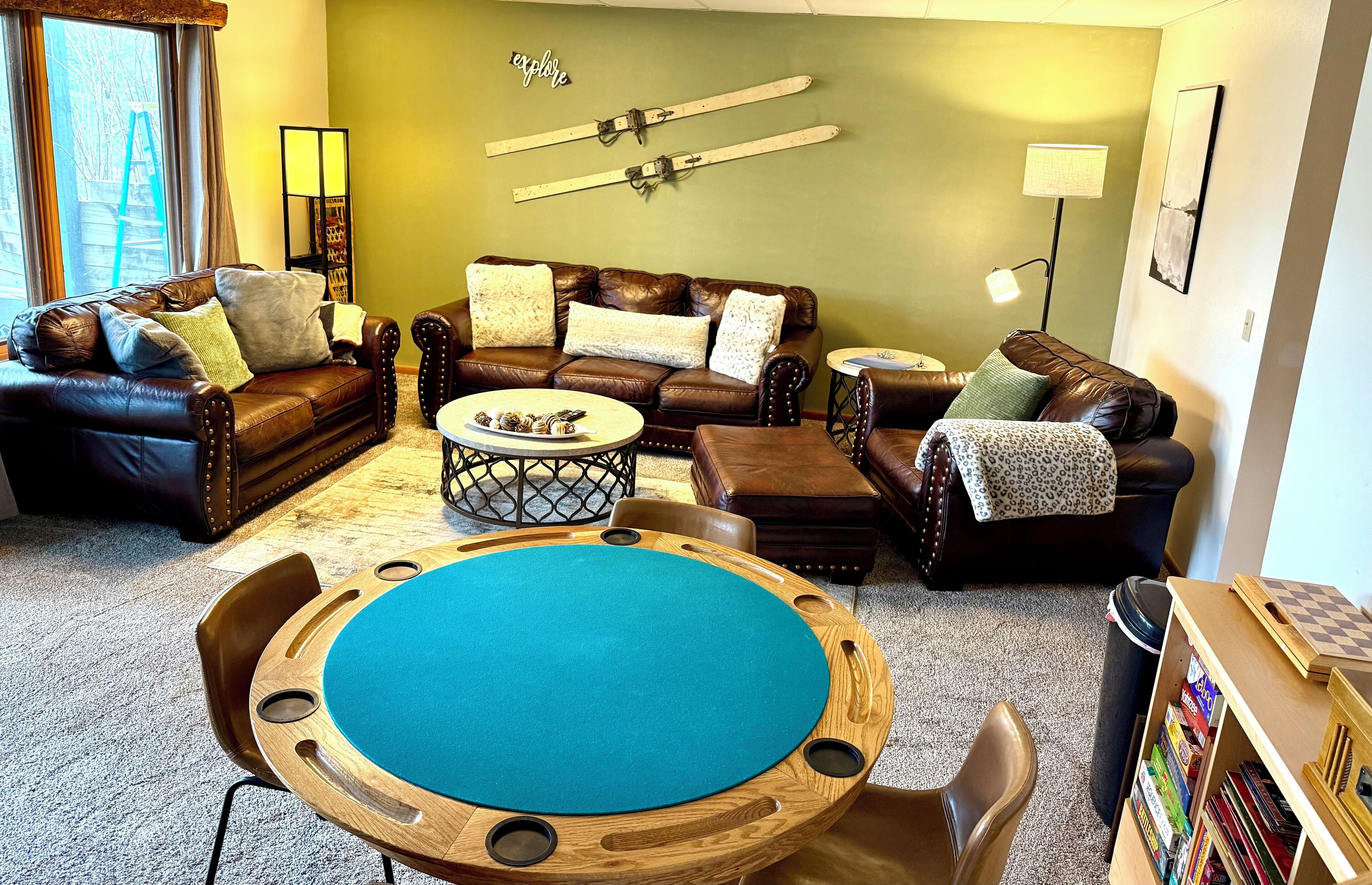 A living room with a pool table, leather couches, and a wall-mounted ski rack.