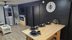 Eine moderne Küche mit Holztisch, gedecktem Esstisch, einer schwarzen Wanduhr und einem eingebauten Kamin.