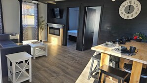 Ein modernes Wohnzimmer mit Kamin, einem Essbereich mit Holztisch und einer großen Wanduhr.