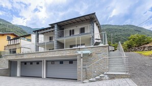 A modern two-story house with a garage, stone steps, and a balcony.