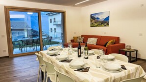 A dining area with a table set for four, a red sofa, and a painting on the wall.
