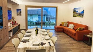 A dining area with a table set for six, a sofa, and a TV on the left.