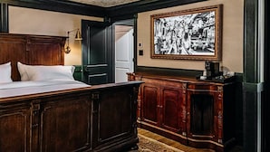 Un dormitorio con una cama de madera grande, un escritorio con una lámpara y un cuadro en la pared.