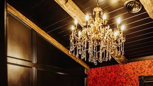 Una cama con edredón blanco y almohadas, un cabecero de madera y un candelabro colgante.