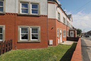 Ein zweistöckiges Wohnhaus mit Ziegelaußenwand, Holzzaun und blauem Himmel.