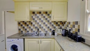A compact kitchen with a washing machine, a sink, and a coffee maker.