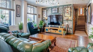 A modern living room with a large TV, leather sofa, and a chandelier.