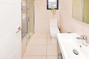Un baño con inodoro, lavamanos y zona de ducha.