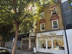 Ein Schaufenster mit einem Schild für 'Queen Nails' und einer verschlossenen Tür mit Graffiti.