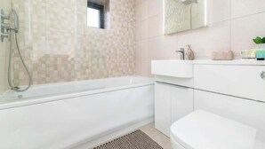 A modern bathroom with a bathtub, a shower, a sink, and a mirror.