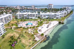 A resort with multiple buildings, a central pool, and a beach area.