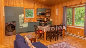 A cabin interior with a dining area, kitchen, and a washing machine. - Lake View Loft Studio type (Severn)