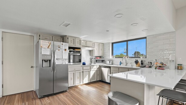 Una cocina moderna con electrodomésticos de acero inoxidable, armarios blancos y un amplio ventanal con vistas.