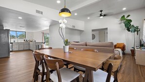 Una cocina amplia con comedor, piso de madera y una lámpara colgante moderna.