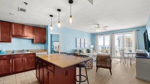 A modern kitchen with a central island, wooden cabinets, and pendant lighting.