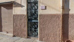 A building with a metal gate, a window with a geometric pattern, and a sign on the wall. - GuestHost - Cozy 87 sqm apartment, for 6 people, located on the first floor of a building (NO lift). The accommodation is located in the heart of the historic Ballarò market (in a restricted traffic zone), an area where it is possible to savor the true  (Palermo)