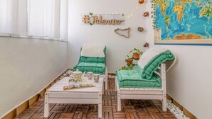 A cozy room with two green cushioned chairs, a white coffee table, and a world map on the wall. - GuestHost - Cozy 87 sqm apartment, for 6 people, located on the first floor of a building (NO lift). The accommodation is located in the heart of the historic Ballarò market (in a restricted traffic zone), an area where it is possible to savor the true  (Palermo)