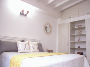 Une chambre à coucher comprenant un lit, une table de chevet, une armoire et un miroir fixé au mur.