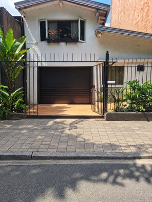 A residential property with a garage door, a fenced driveway, and a small garden area with plants.