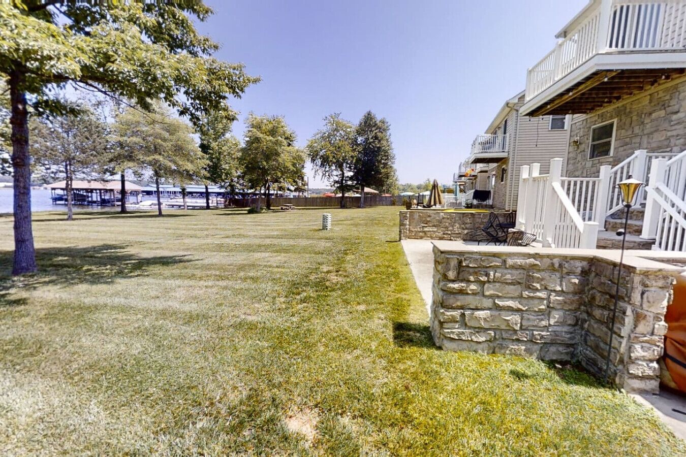 A backyard with a stone patio, a grassy lawn, and a building with a balcony.