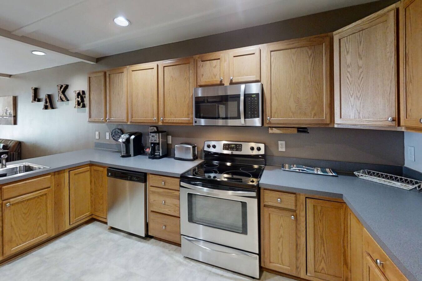 A modern kitchen with wooden cabinets, stainless steel appliances, and a built-in microwave.