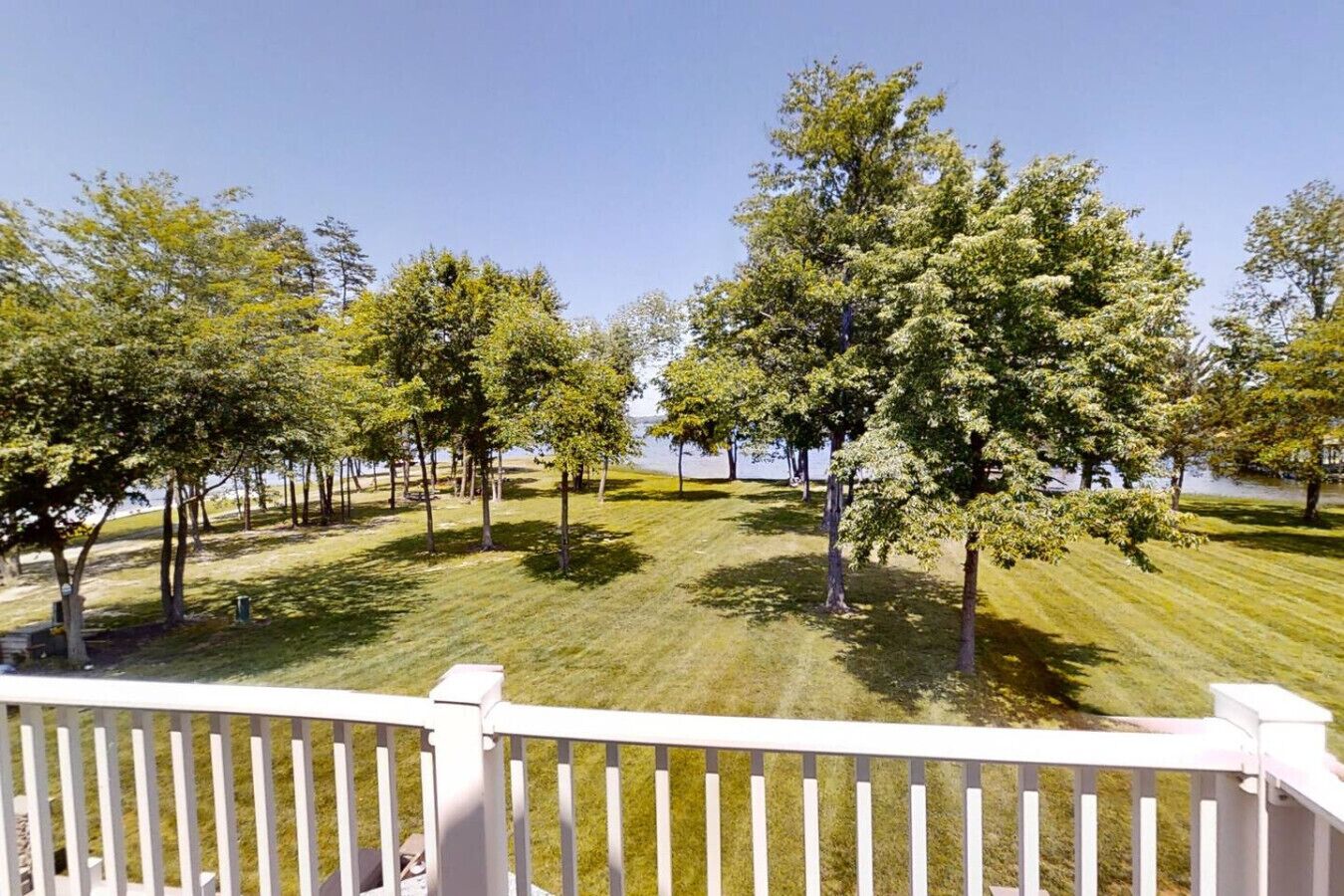 A grassy area with trees and a white fence.