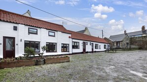 A row of white buildings with red-tiled roofs, a gravel courtyard, and a stone wall. - 1 Bedroom bolthole in Seahouses (Seahouses)