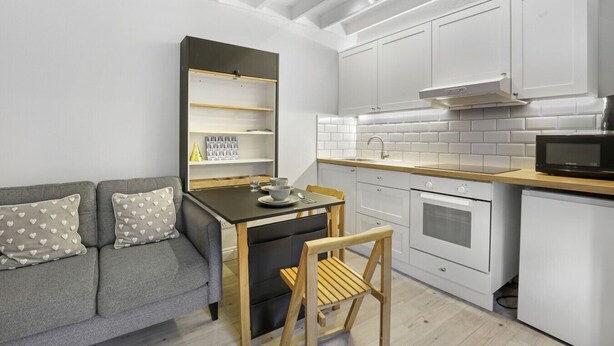 A compact kitchen with white cabinets, a black countertop, and a wooden chair. - 1 Bedroom bolthole in Seahouses (Seahouses)