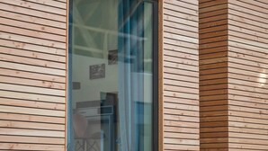 A modern wooden cabin with a large window, exposed wooden beams, and a rustic interior.