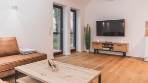 A modern living room with a sofa, a coffee table, a TV, and a plant.