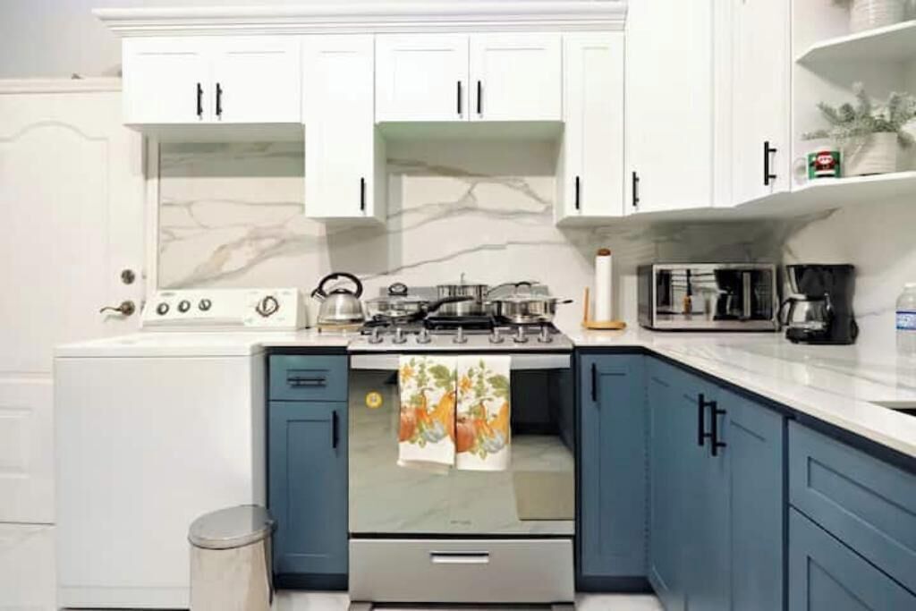 A kitchen with white cabinets, a stove, and a microwave.