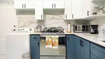 A kitchen with white cabinets, a stove, and a microwave.
