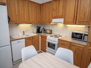 Una cocina pequeña con armarios de madera, una estufa blanca, un microondas y un lavamanos.