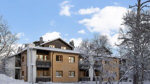 Un immeuble à plusieurs étages, doté d’une façade en briques, de balcons et surplombant un paysage enneigé.