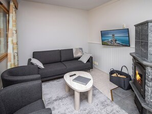 Een moderne woonkamer met een grijze bank, een ronde salontafel en een open haard.