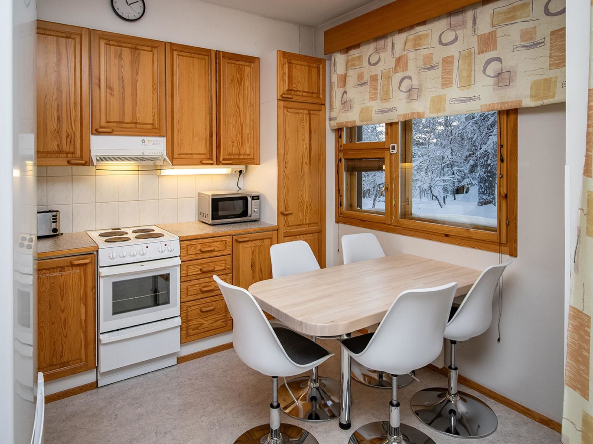 A kitchen with wooden cabinets, a microwave, a stove, and a dining area with a table and chairs.