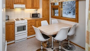 Une cuisine dotée de meubles en bois, d’un four à micro-ondes, d’une cuisinière et d’un coin repas avec une table et des chaises.