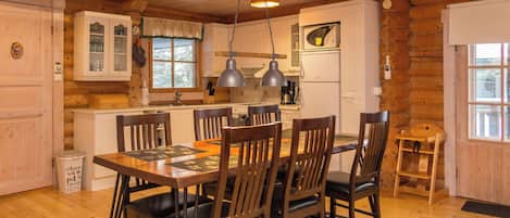 Un interior de madera con una mesa de comedor, sillas y una zona de cocina.