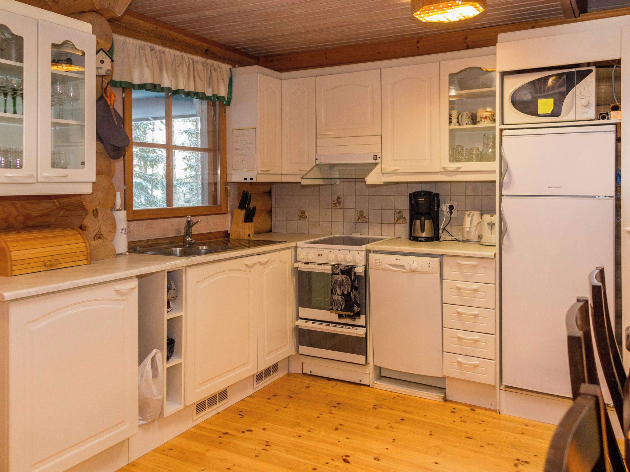 A kitchen with white cabinets, a wooden countertop, a sink, a stove, a dishwasher, and a microwave.