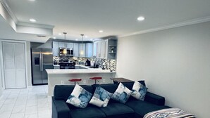 Ein modernes Wohnzimmer mit einem dunkelblauen Sofa, einem Holztisch und einer gemusterten Decke.