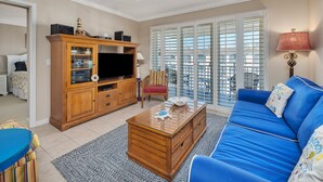 A living room with a blue sofa, wooden entertainment center, and a television. - Enjoy Island Living at Oceanfront Condominium! Inc (Saint Simons Island)