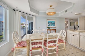 A dining area with a table and chairs, a chandelier, and a view of the outside.